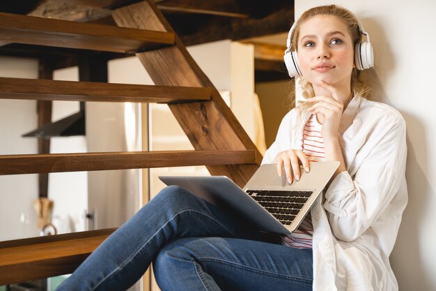 Voel het moment. Opgetogen blonde die positiviteit uitdrukt, zittend op houten trappen