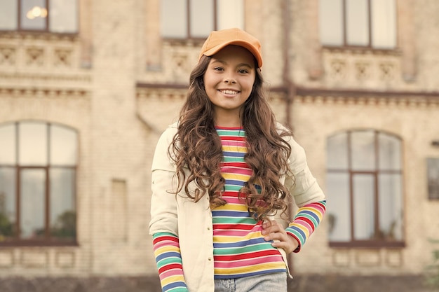 Voel je vrij en gelukkig kind schoonheid en mode vrolijk schoolmeisje dragen pet tiener in casual stijl kapper jeugd geluk gelukkig meisje met lang krullend haar mooi kind glimlachend buiten