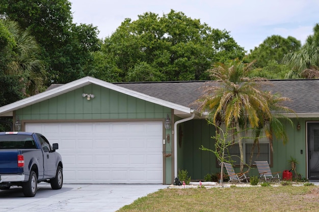 Foto voertuig geparkeerd voor een brede garage met een dubbele deur op een geplaveide oprit van een typisch hedendaags amerikaans huis