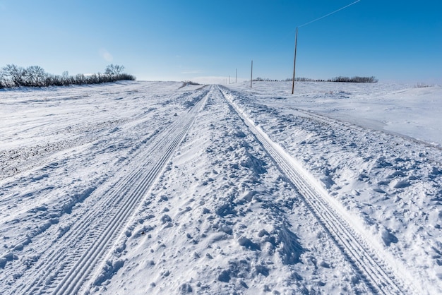 Voertuigsporen door diepe sneeuw op een landelijke weg in saskatchewan, canada