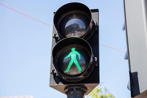 Voet groen verkeerslicht op blauwe hemelachtergrond