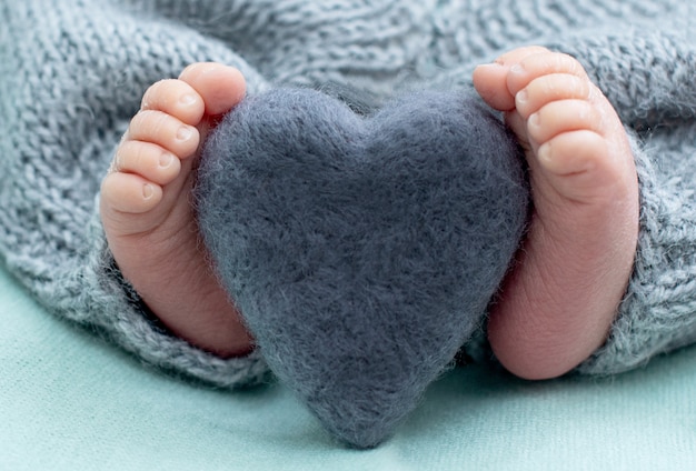 Voet van de pasgeboren baby met wollen hart, tederheid. kopie ruimte in winter concept