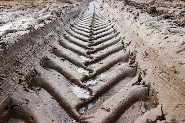 Voetafdruk van het wielloopvlak op de grondweg Het spoor van het loopvlak van vrachtwagenswielen Het loopvlakafdruk van de autoband op zand achtergrondtextuur Voetafdrukken rubberen banden van auto