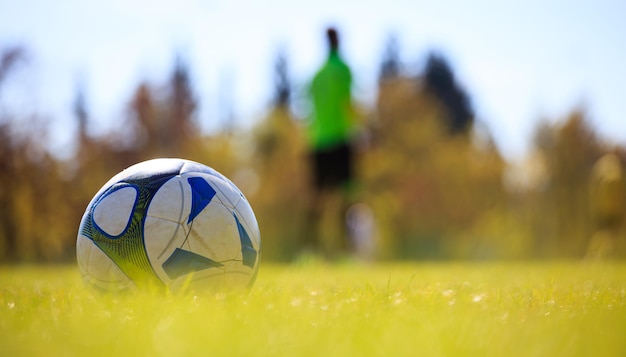 Voetbal in het veld aan de linkerkant klaar om te worden geschopt Vage speler en natuur achtergrond