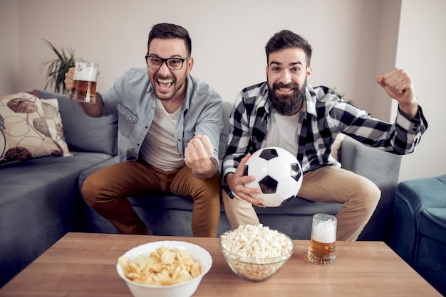 Voetbalfans met popcorns en bier kijken naar spel