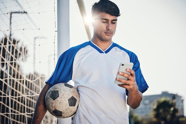 Voetballen telefoon en man op het veld voor wedstrijd training of fitness nieuws sociale media chat en blog Voetballer of persoon zoeken op mobiele app voor sport informatie gezondheid of doelen controleren