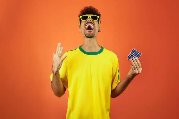 Voetballer Black Man vieren met fotovoltaïsch zonnepaneel geïsoleerd op oranje achtergrond