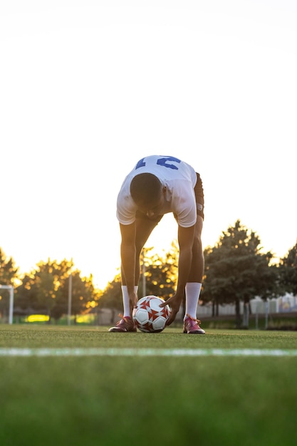 Voetballer die de bal op het gras plaatst Lage hoek van voetballer die de bal in vrije trap op het gras legt