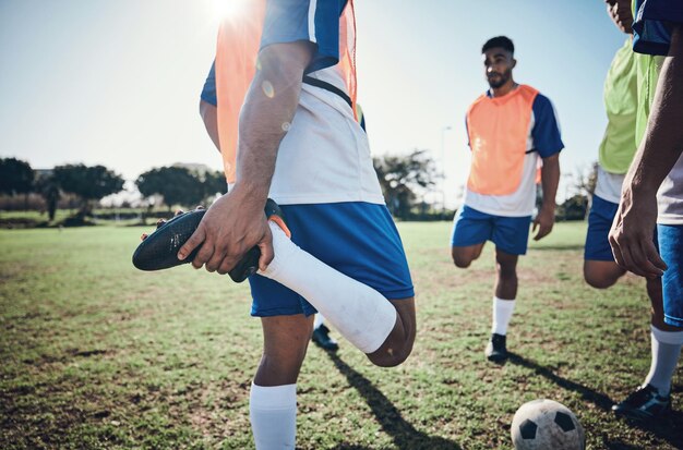 Foto voetballer die zijn benen strekt en mannen die op een veld trainen voor sportspel en fitness mannelijk voetbalteam of atleetgroep buiten voor uitdagende training of opwarming op een grasveld