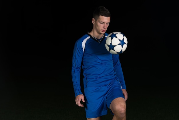 Voetballer doet schop met bal op voetbalstadion veld geïsoleerd op zwarte achtergrond