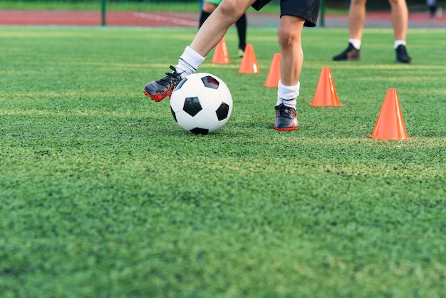 Voetballer met bal onder oranje kegels