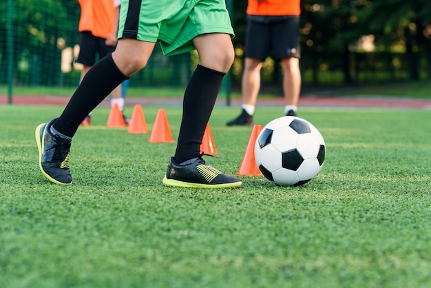 Voetballer met bal onder oranje kegels