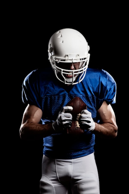 Voetballer met nummer op een blauw uniform en een bal in de hand.