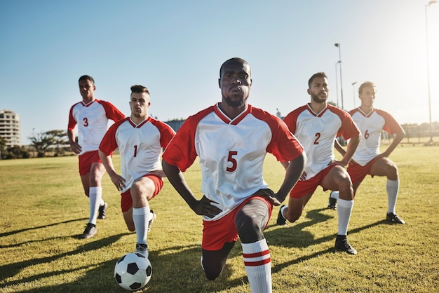 Voetbalmannen en team strekken zich uit op het veld voor een sportwedstrijd of trainingsoefening Gezondheidsfitness en teamwerk Voetbalcompetitiespelers strekken zich samen uit op gras voor sterke prestaties in de wedstrijd