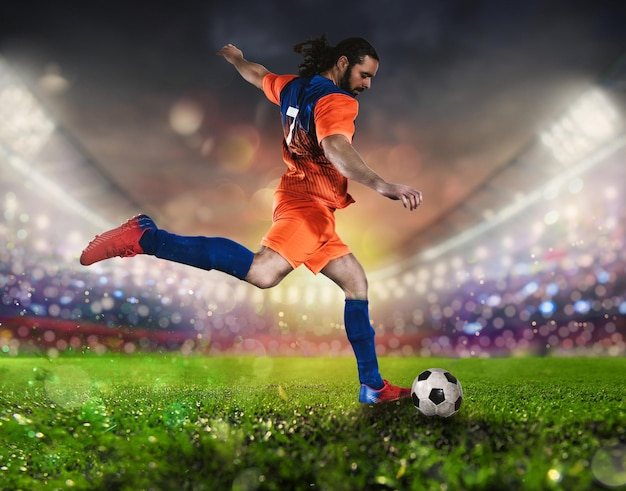 Voetbalscene's nachts met een speler in een oranje uniform die de bal met kracht schopt
