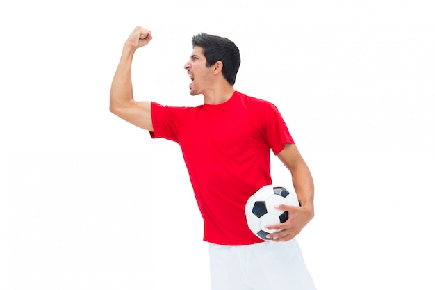 Voetbalster in rode holding bal en het toejuichen