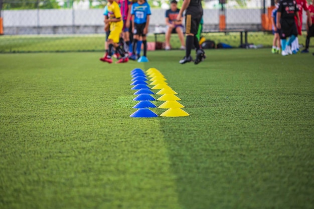 Voetbaltactieken op grasveld met barrièrekegel voor het trainen van de springvaardigheid van kinderen in de voetbalacademie