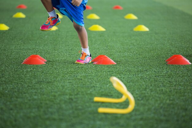 Voetbaltactieken op grasveld met kegel voor het trainen van de springvaardigheid van kinderen in de voetbalacademie