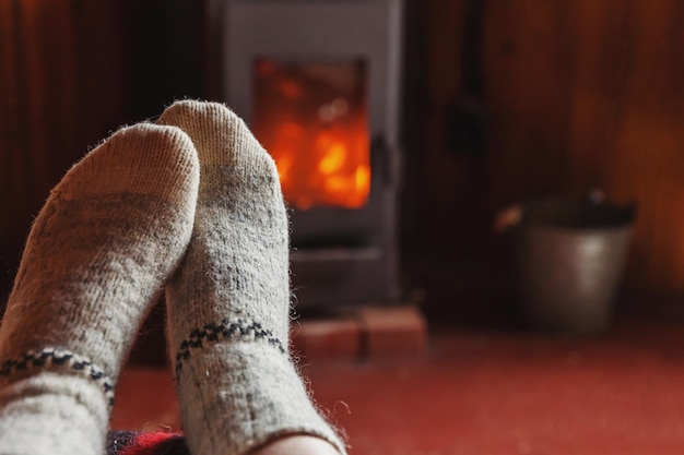 Voeten benen in winterkleren wollen sokken bij open haard achtergrond vrouw om thuis te zitten in de winter of au