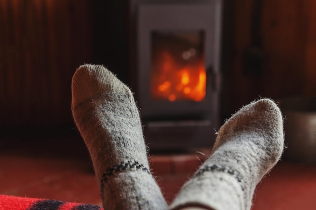 Voeten benen in winterkleren wollen sokken bij open haard achtergrond vrouw om thuis te zitten op winter of au...