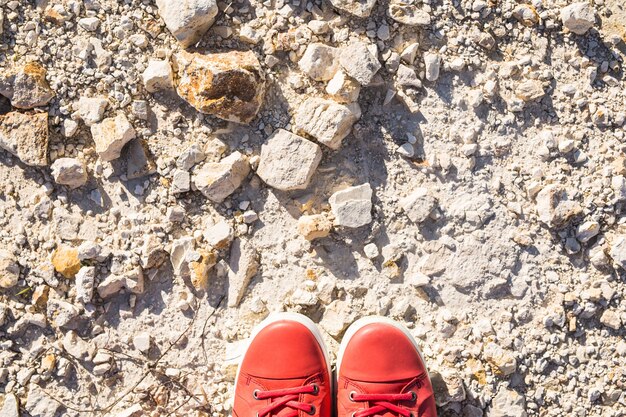 Voeten in casual roze schoenen op de stenen achtergrond.