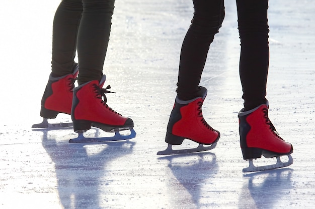 Voeten in rode schaatsen op een ijsbaan. Sport en amusement. Rust- en wintervakanties.