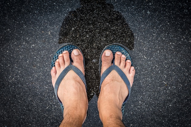 voeten in sandalen van Aziatische mannen benen met natte straat