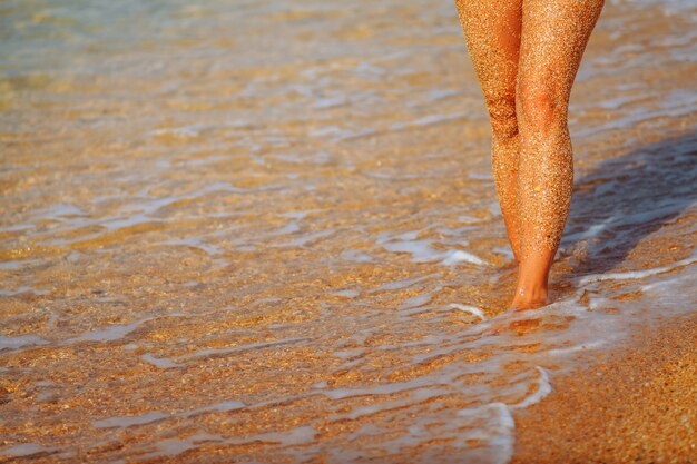 Voeten meisje op het strand. Golven die naar de kust lopen