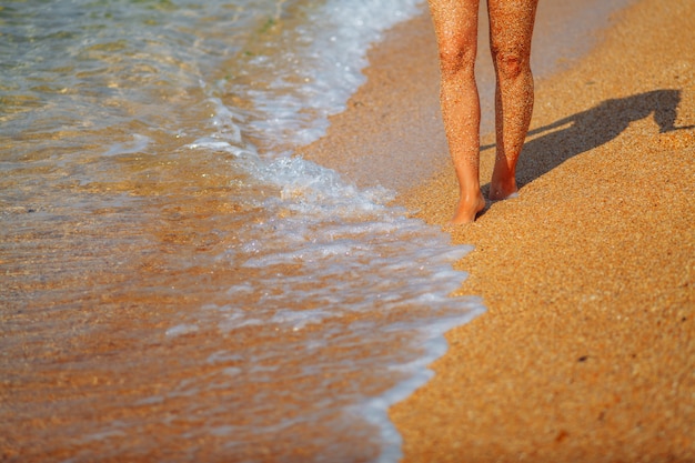 Voeten meisje op het strand. Golven die naar de kust lopen