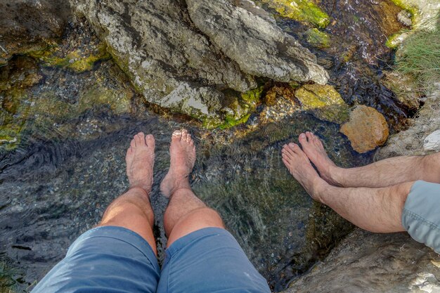 Voeten ondergedompeld in het heldere water met kleine rotsen van een bergrivier