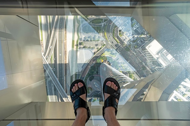 Voeten op de glazen vloer van een hoge wolkenkrabber een gevaarlijke enge blik Toeristen poseren op een glazen vloer in wolkenkrabber