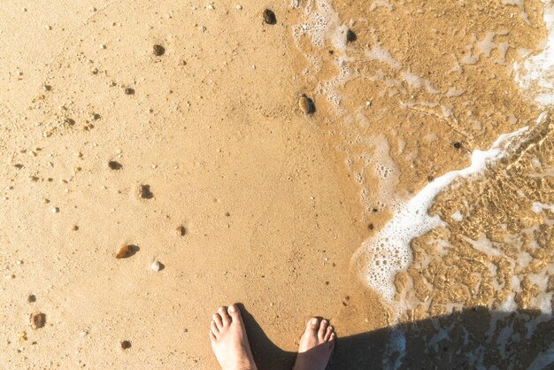 Foto voeten op het strand en een zeegolf nat zand zonnige stranddag vakantie