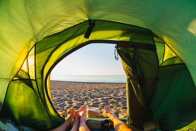 Voeten uit een tent met uitzicht op de kust