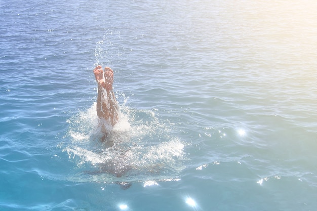 Foto voeten van een man die in de oceaan springt