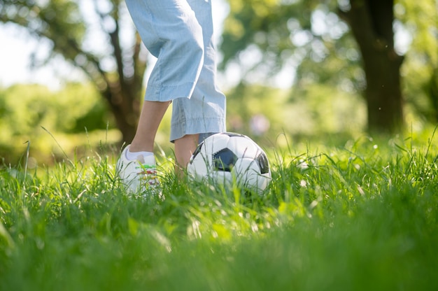 Voeten van junior kind met voetbal op gras