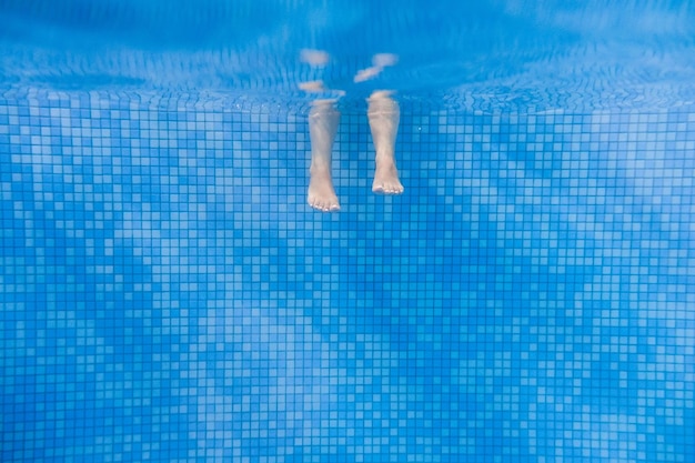 Voeten van mensen bewegen onder water in het zwembad Kinderbenen Zomer Grappige onderwaterbenen in zwembad onder water weergave van vrouwen of kinderen vakantie en sport concept
