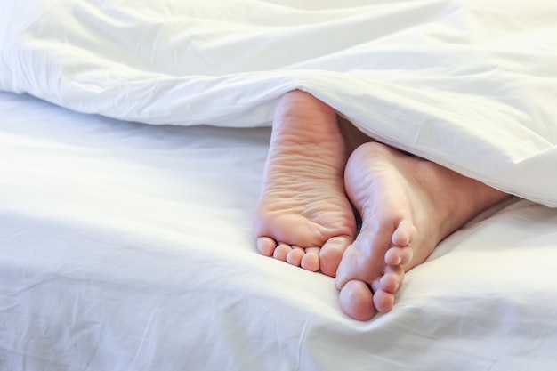 Voeten van slapende vrouw in het bed