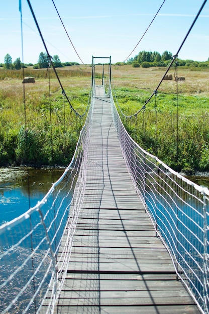 Voetgangershangbrug over de rivier op een zomerdag Verticale foto