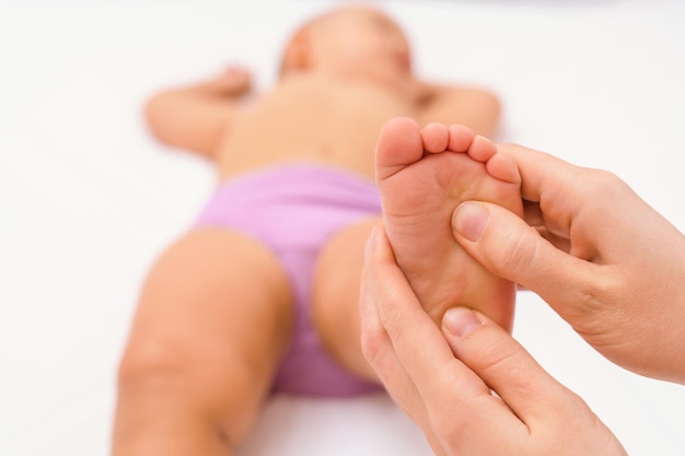 Voetmassage voor een pasgeboren baby, een moeder geeft een voetmassage aan een kind. Selectieve focus op de hiel van de baby