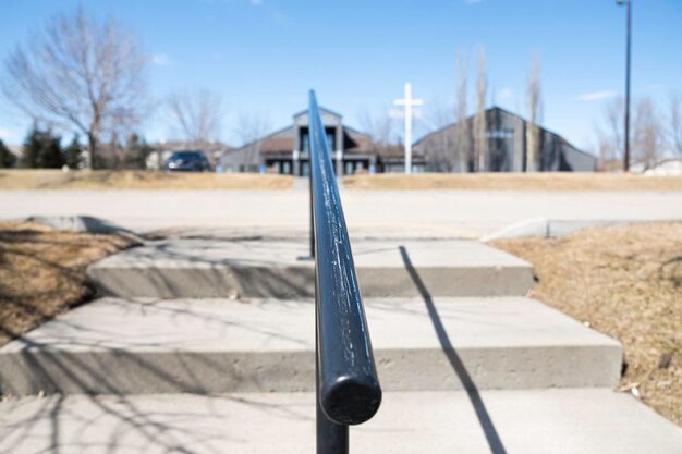 Voetstappen in de aanloop naar een kerkgebouw met kruis wazig achter boom