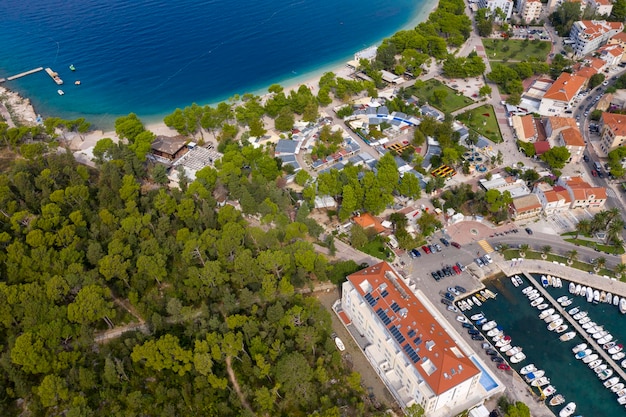 Vogelperspectief van de gebogen kustlijn en de stad Makarska Kroatië Schepen in de groene bossen van de haven