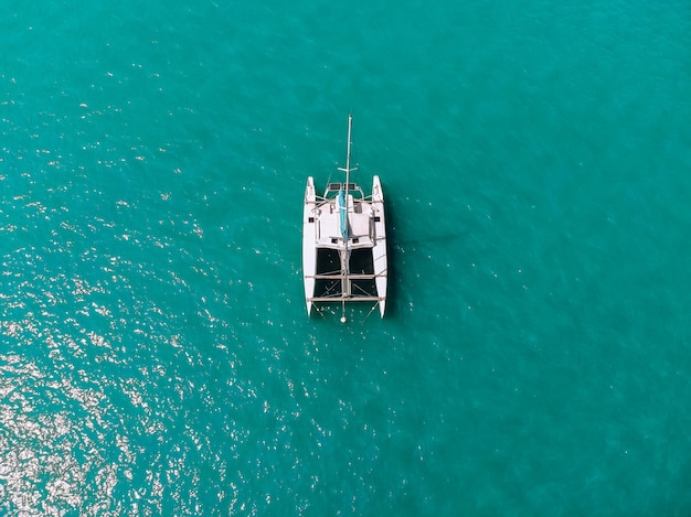 Vogelvlucht van de verbazingwekkende witte catamaran die over de blauwe lagune vaart. Bovenaanzicht.