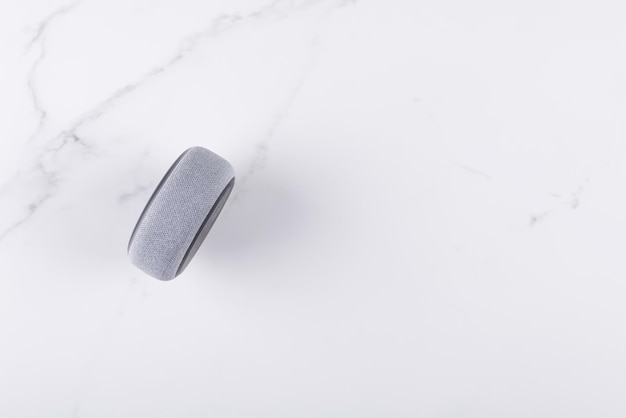 Voice controlled wireless speaker and personal assistent for home on a white marble background top view