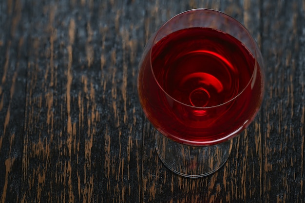 Vol glas rode wijn op een zwarte houten tafel, tophoek.