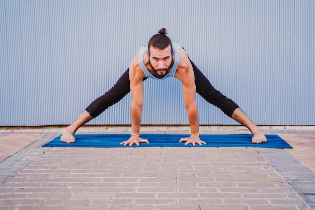 Foto vol lengte van de man die yoga doet op een oefenmat tegen de muur