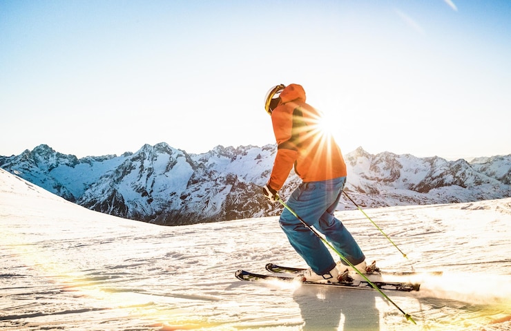 Foto vol lengte van een man die op een besneeuwde berg tegen de lucht staat