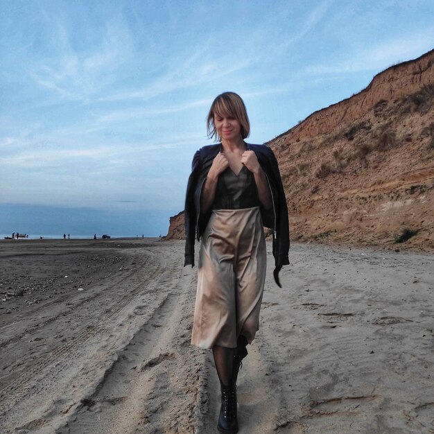 Foto vol lengte van jonge vrouw die op het strand staat