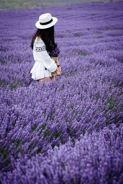 Vol lengte van jonge vrouw met bloemen op het veld