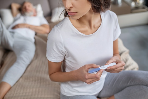 Voldoen aan verwachtingen. Een jonge vrouw die haar positieve zwangerschapstest houdt