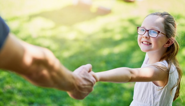 Volg me pap, ik weet de weg naar het park Bijgesneden opname van een klein meisje dat haar vaders hand buiten vasthoudt